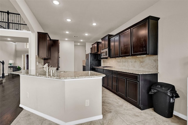 kitchen with sink, stainless steel appliances, kitchen peninsula, and light stone counters