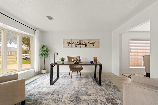 office area with light hardwood / wood-style floors and a textured ceiling