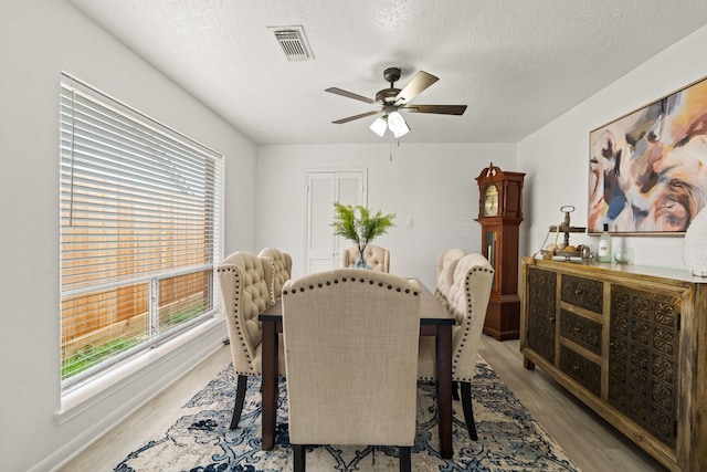 dining space featuring light wood-type flooring, a textured ceiling, and ceiling fan