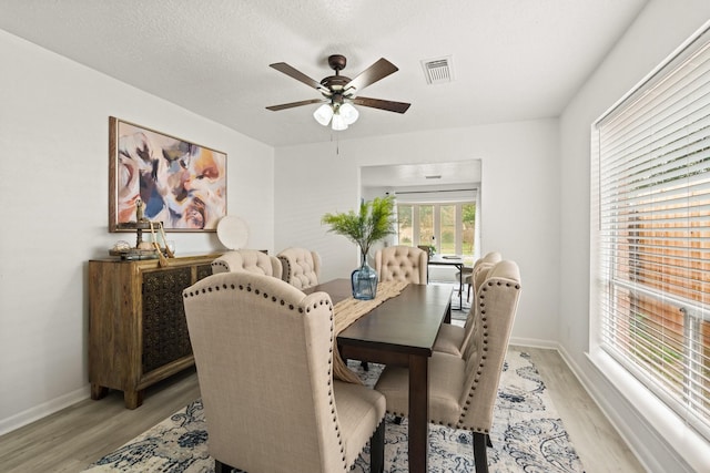 dining room with a textured ceiling, ceiling fan, and light hardwood / wood-style flooring