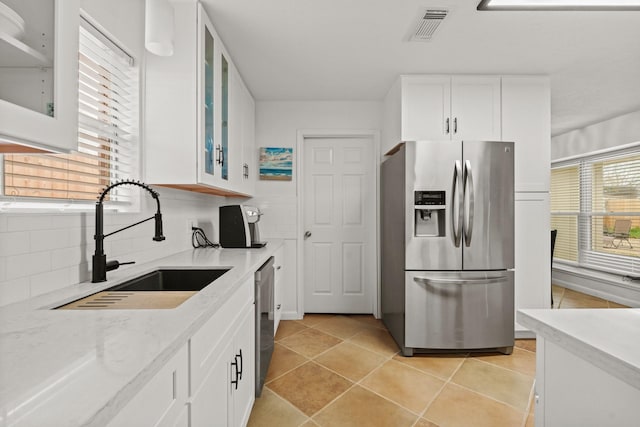 kitchen with appliances with stainless steel finishes, sink, light stone counters, and white cabinets