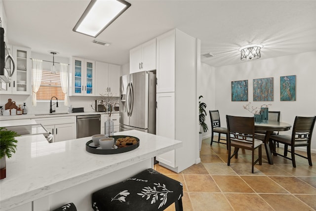 kitchen featuring white cabinetry, sink, stainless steel appliances, and decorative light fixtures