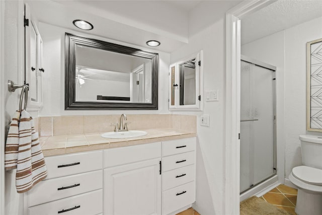 bathroom with vanity, toilet, a shower with shower door, and tile patterned floors