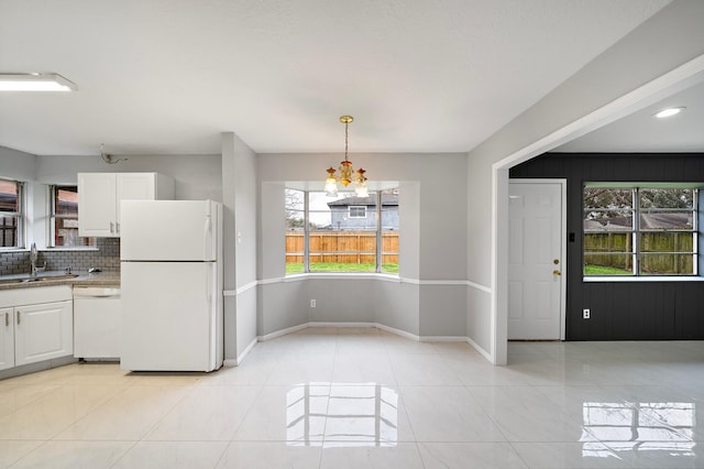 kitchen featuring hanging light fixtures, sink, white appliances, tasteful backsplash, and white cabinets