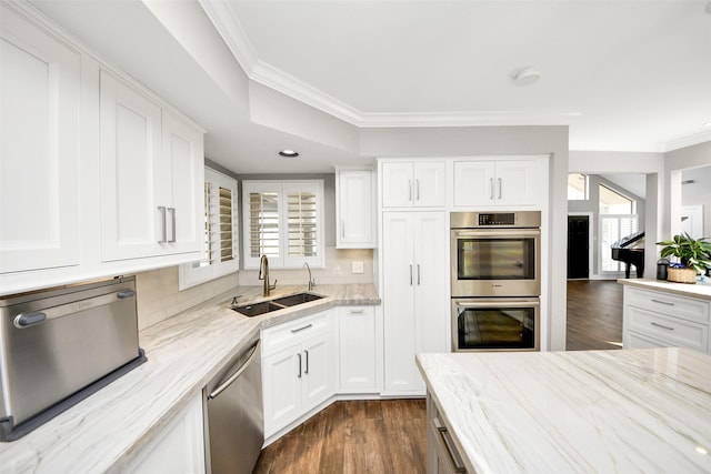 kitchen featuring light stone counters, a sink, white cabinets, appliances with stainless steel finishes, and dark wood finished floors