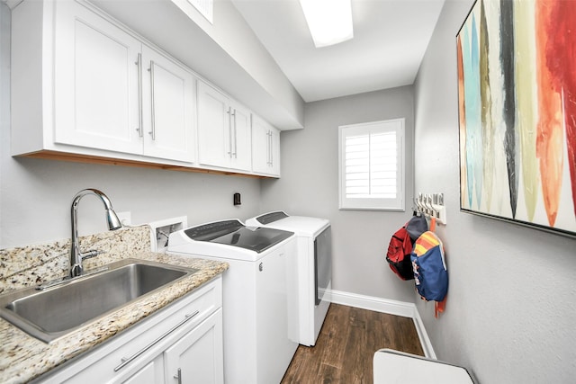 clothes washing area with dark wood-style flooring, a sink, baseboards, washer and dryer, and cabinet space