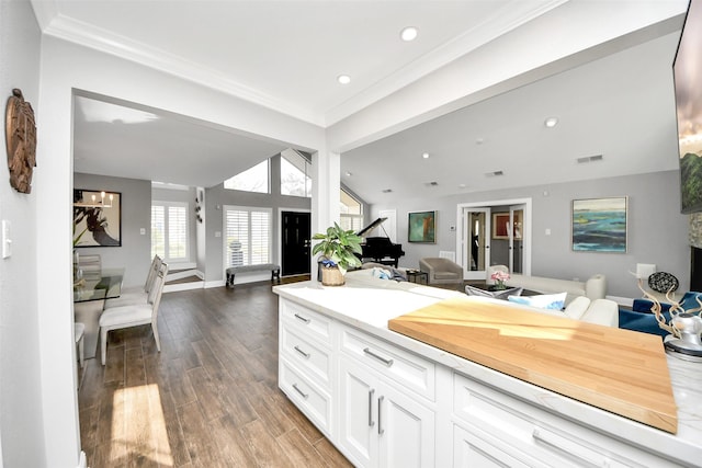 kitchen featuring baseboards, white cabinets, lofted ceiling, open floor plan, and wood finished floors