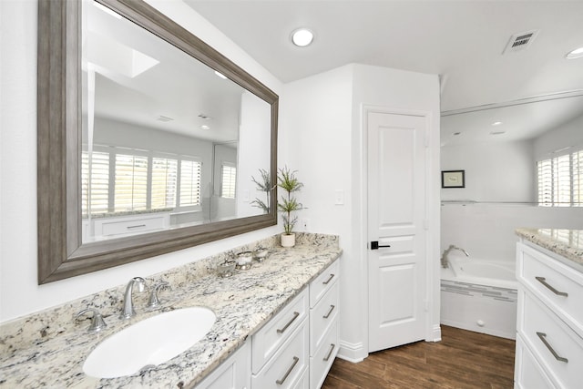 full bath with visible vents, wood finished floors, a garden tub, vanity, and recessed lighting