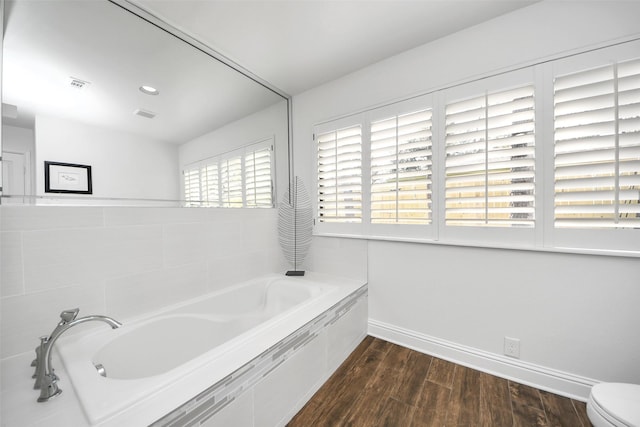 full bathroom with visible vents, a garden tub, baseboards, and wood finished floors