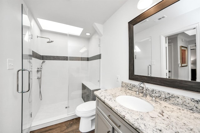 full bathroom featuring toilet, a skylight, wood finished floors, visible vents, and a shower stall