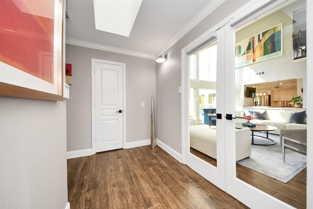 doorway with a skylight, visible vents, baseboards, wood finished floors, and crown molding