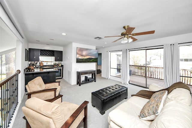 living area with light colored carpet, wet bar, a healthy amount of sunlight, and visible vents