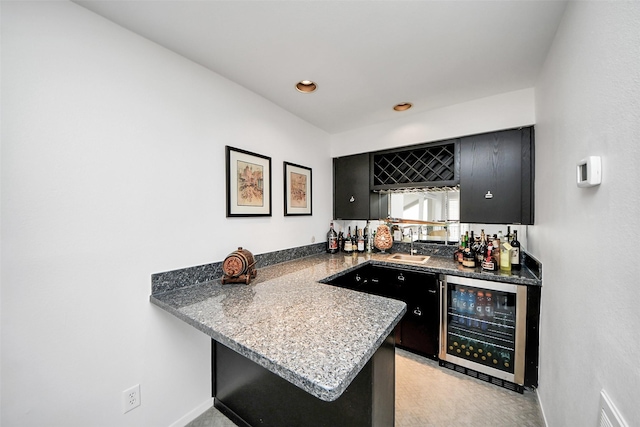 bar featuring recessed lighting, a sink, a bar, beverage cooler, and baseboards