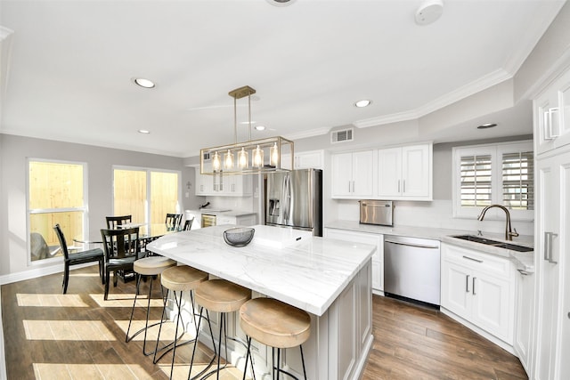 kitchen with stainless steel appliances, visible vents, white cabinetry, a sink, and a kitchen island