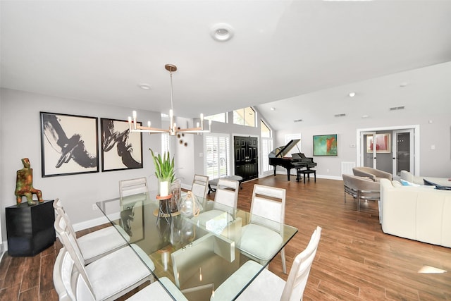 dining space with visible vents, an inviting chandelier, vaulted ceiling, wood finished floors, and baseboards