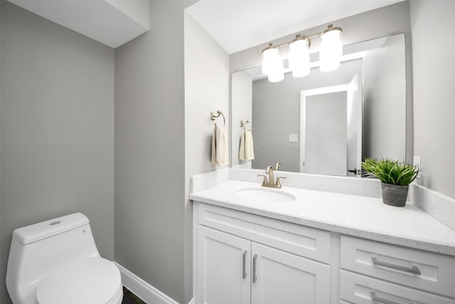 half bathroom featuring baseboards, vanity, and toilet