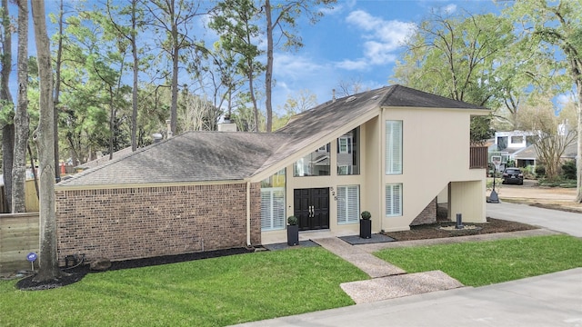 view of front of house featuring a shingled roof, brick siding, a chimney, and a front lawn