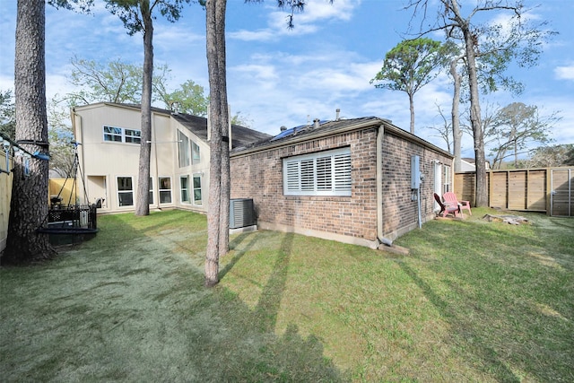 rear view of house with a yard, brick siding, and fence