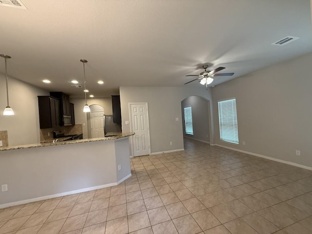 kitchen with light stone counters, ceiling fan, stainless steel appliances, kitchen peninsula, and tasteful backsplash