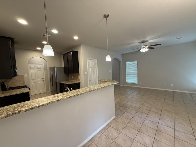 kitchen with light stone countertops, ceiling fan, decorative light fixtures, stainless steel fridge, and light tile patterned floors