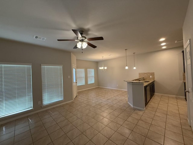 kitchen with light tile patterned floors, light stone countertops, hanging light fixtures, and ceiling fan with notable chandelier