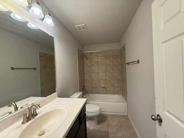 full bathroom featuring vanity, a textured ceiling, tiled shower / bath combo, toilet, and tile patterned floors