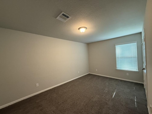 unfurnished room featuring dark colored carpet and a textured ceiling