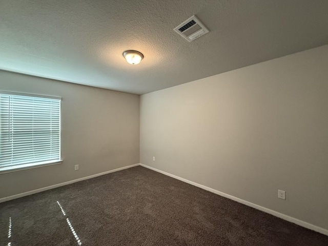 unfurnished room with dark colored carpet and a textured ceiling