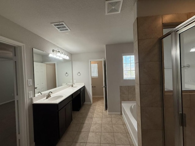 bathroom with a textured ceiling, plus walk in shower, vanity, and tile patterned flooring