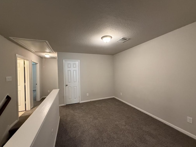 empty room featuring dark carpet and a textured ceiling