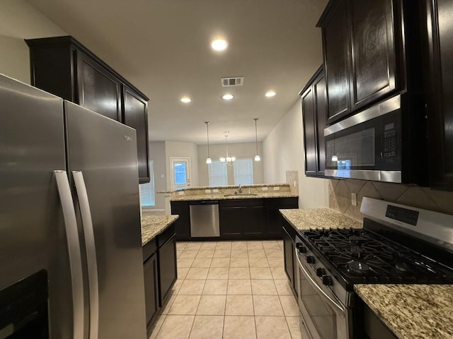 kitchen featuring tasteful backsplash, hanging light fixtures, stainless steel appliances, light tile patterned floors, and sink