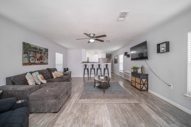 living room featuring ceiling fan, wood-type flooring, and a textured ceiling