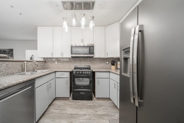 kitchen with sink, appliances with stainless steel finishes, white cabinets, and pendant lighting