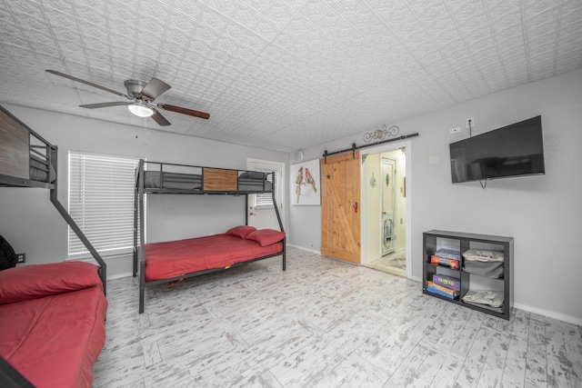 bedroom with ceiling fan, a barn door, and light wood-type flooring