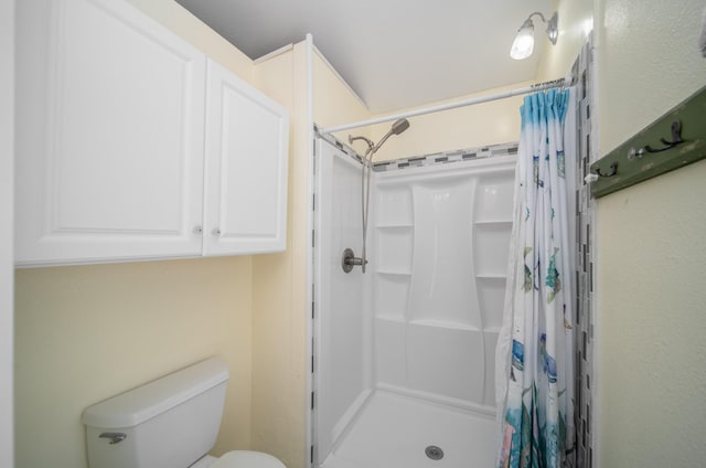 bathroom featuring toilet and curtained shower