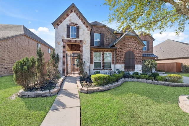 view of front facade with stone siding, a gate, fence, a front lawn, and brick siding