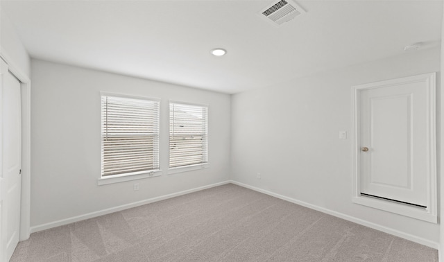 unfurnished room featuring baseboards, visible vents, and light colored carpet