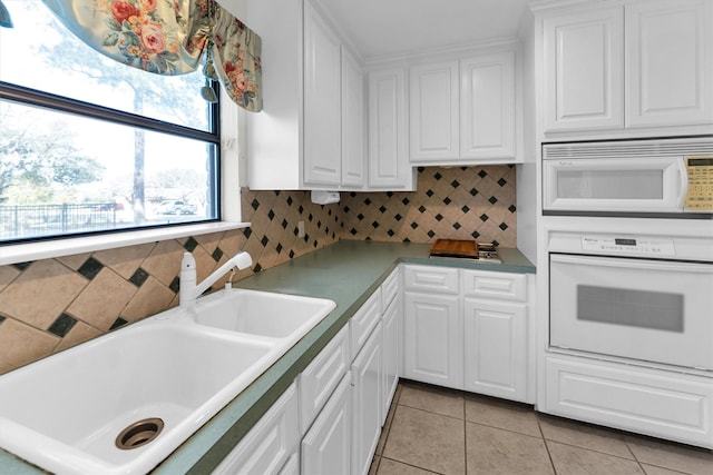 kitchen featuring sink, white appliances, white cabinetry, and light tile patterned floors