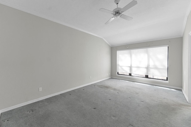 carpeted empty room with crown molding, vaulted ceiling, baseboards, and ceiling fan