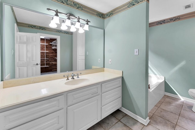 bathroom featuring tile patterned floors, vanity, baseboards, a garden tub, and toilet