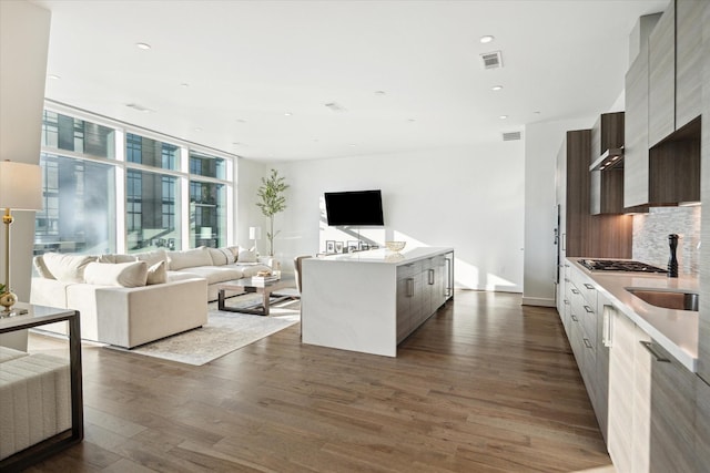 kitchen with stainless steel gas stovetop, a center island, backsplash, sink, and dark hardwood / wood-style floors