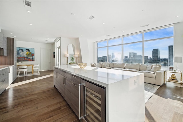 kitchen featuring a wall of windows, beverage cooler, a center island, and dark hardwood / wood-style flooring