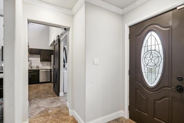 foyer entrance with ornamental molding and a barn door