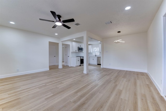 unfurnished living room featuring light wood-type flooring, ceiling fan, and a textured ceiling