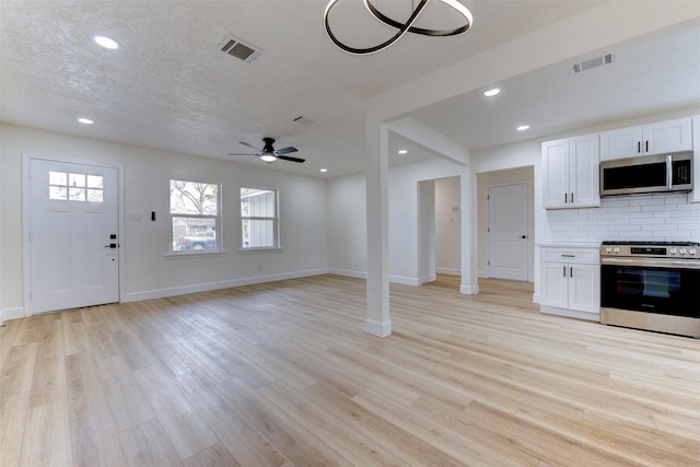 kitchen featuring stainless steel appliances, light hardwood / wood-style flooring, backsplash, a textured ceiling, and white cabinets