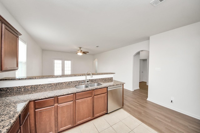 kitchen featuring visible vents, arched walkways, dishwasher, dark stone countertops, and a sink