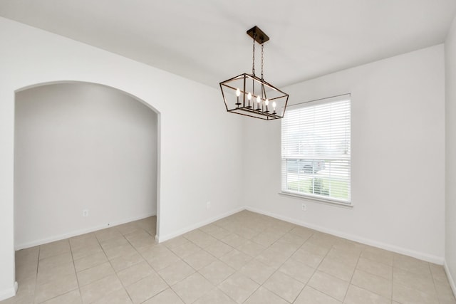 spare room with arched walkways, baseboards, and light tile patterned floors