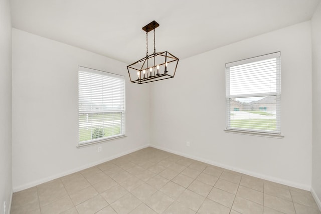 unfurnished room with a notable chandelier and baseboards