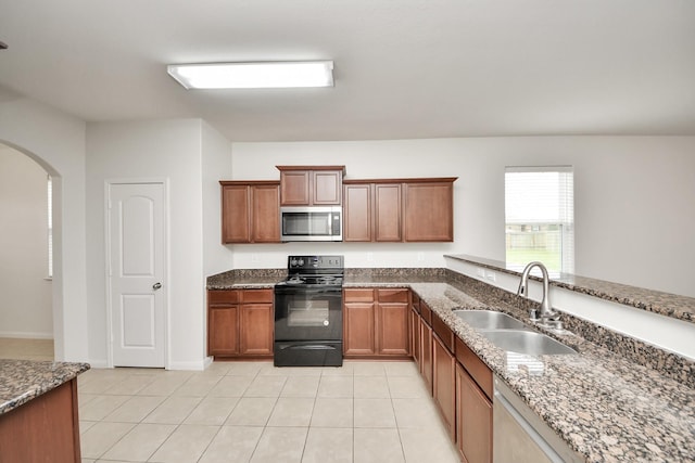 kitchen with light tile patterned floors, arched walkways, stainless steel microwave, black electric range, and a sink