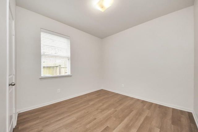 spare room featuring light wood finished floors and baseboards